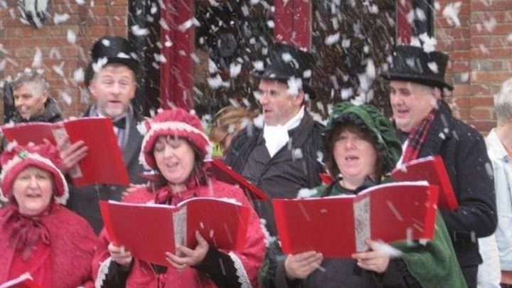 Carol singers in traditional dress performing at a Christmas event in Battle