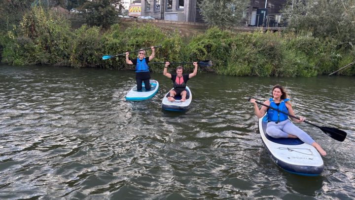 Three people enjoying a paddleboarding activity during an East Sussex group break